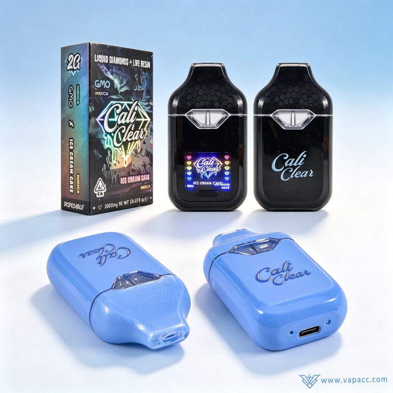 Close-up of Empty Cali Clear 2g dual chamber vape wholesale black and light blue hardware next to GMO x Ice Cream Cake packaging box.