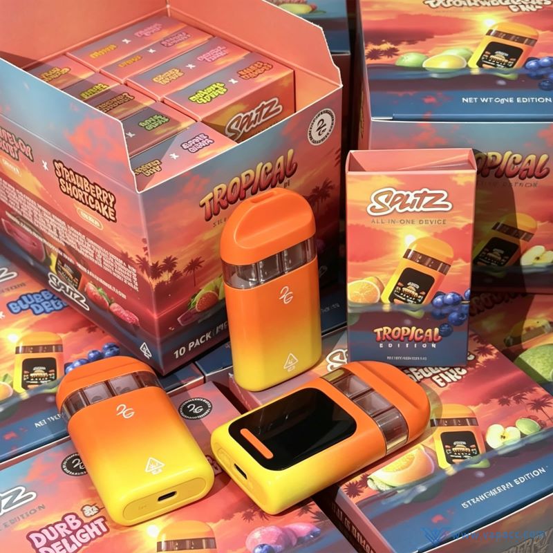 Splitz 2g Empty Tropical Edition dual-chamber disposable vape hardware lying on top of colorful strain packaging boxes.