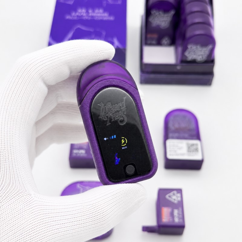Hand holding purple Wizard Trees 1g single-flavor empty vape device displaying active battery screen graphics