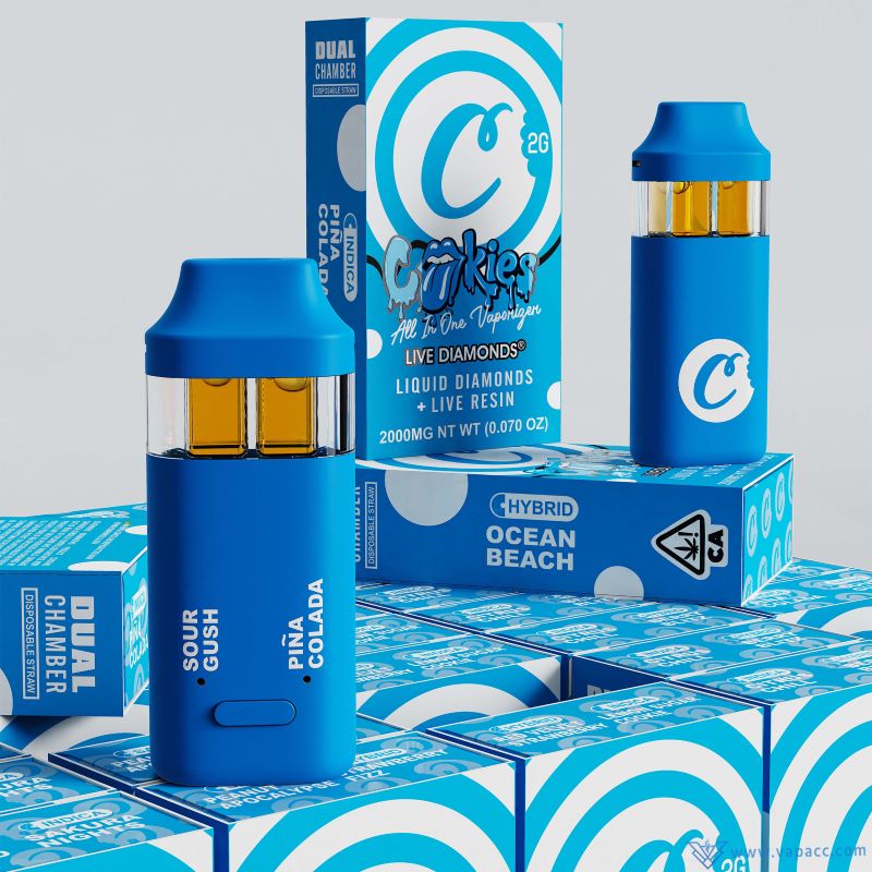 Close up view of blue Cookies 2ml dual tank empty disposable vape pens standing on strain packaging boxes.
